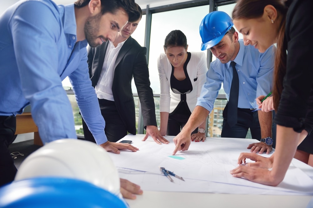 business people group on meeting and presentation  in bright modern office with construction engineer architect and worker looking building model and blueprint planbleprint plans for biofilter living wall