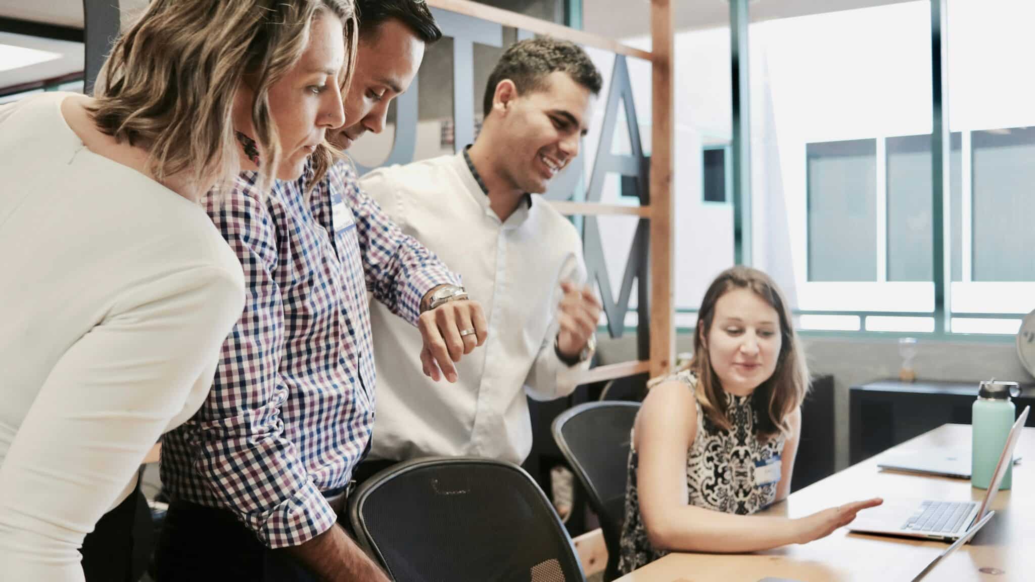 a group of people looking at a laptop in the office