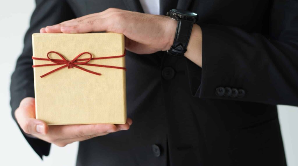 man in a suit holding a gift box