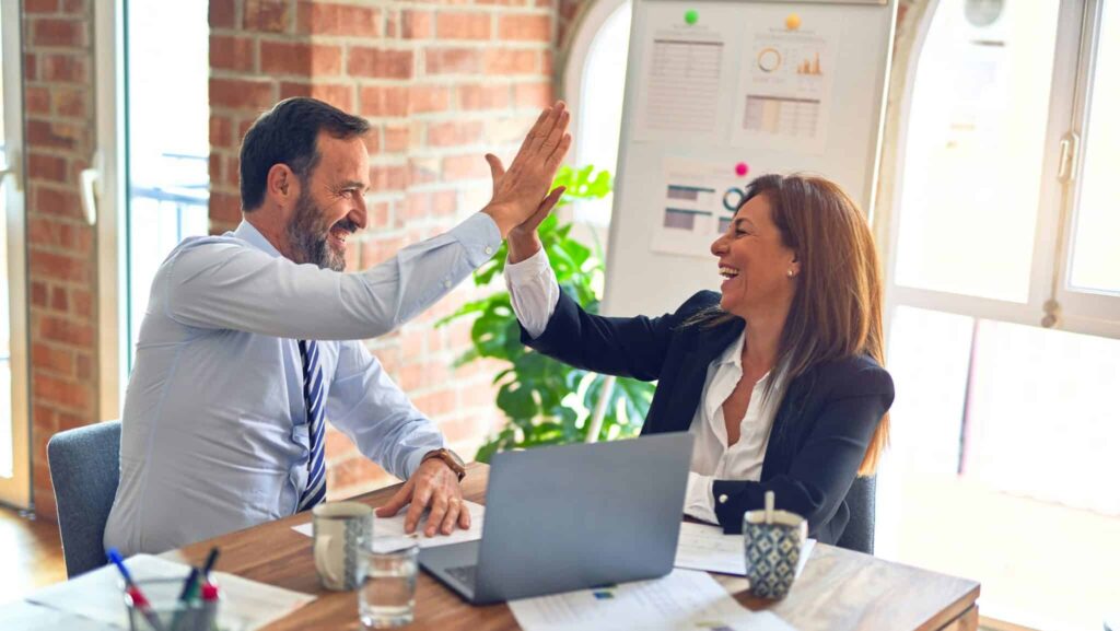 a man and a woman in the office doing a high-five